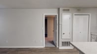 This single-floor residence at 500 Maxham Rd in Austell, Georgia offers a well-designed layout with functional living spaces throughout. The kitchen is a standout feature, showcasing white cabinetry, a mosaic tile backsplash, light granite-style countertops, and a peninsula that provides additional prep and dining space. Black appliances, including a range, dishwasher, and refrigerator, complement the clean, modern aesthetic. The kitchen flows naturally into the main living area, which is finished with durable wood-look vinyl plank flooring and neutral gray walls that create a bright, open atmosphere. A carpeted bedroom offers a comfortable retreat, with a window allowing natural light to filter in. An additional room, also with wood-look flooring and multiple windows, provides flexible use as a bedroom, office, or secondary living space. The bathroom is well-appointed with a tub-shower combination, a white vanity with granite-style countertop, and a large mirror. Textured ceilings are consistent throughout the unit, and HVAC vents ensure year-round climate comfort. The overall design balances practicality with modern updates, making this a move-in ready space.