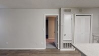 This single-floor residence at 500 Maxham Rd in Austell, Georgia offers a well-designed layout with functional living spaces throughout. The kitchen is a standout feature, showcasing white cabinetry, a mosaic tile backsplash, light granite-style countertops, and a peninsula that provides additional prep and dining space. Black appliances, including a range, dishwasher, and refrigerator, complement the clean, modern aesthetic. The kitchen flows naturally into the main living area, which is finished with durable wood-look vinyl plank flooring and neutral gray walls that create a bright, open atmosphere. A carpeted bedroom offers a comfortable retreat, with a window allowing natural light to filter in. An additional room, also with wood-look flooring and multiple windows, provides flexible use as a bedroom, office, or secondary living space. The bathroom is well-appointed with a tub-shower combination, a white vanity with granite-style countertop, and a large mirror. Textured ceilings are consistent throughout the unit, and HVAC vents ensure year-round climate comfort. The overall design balances practicality with modern updates, making this a move-in ready space.