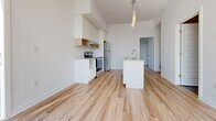 Located at 40 Kirkland Private in Ottawa, this well-appointed 2-bedroom, 1-bathroom unit offers a clean, modern aesthetic across a thoughtfully designed single floor. Light hardwood flooring runs consistently throughout the space, creating a warm and cohesive feel from room to room.

The kitchen is a standout feature, showcasing white cabinetry with open wood-accented shelving, a subway tile backsplash, stainless steel appliances including a full-size refrigerator and electric range, and a central island with a built-in sink and pendant lighting above — ideal for both meal preparation and casual dining.

The two bedrooms are bright and airy, benefiting from large windows that invite generous natural light and offer views of the surrounding neighbourhood and mature trees. The primary bedroom includes access to a dedicated closet, while the second bedroom features a double built-in closet, providing ample storage. Both rooms are finished with the same light hardwood floors and crisp white walls.

The bathroom is elegantly finished with large-format grey tile flooring, a full soaker tub with a glass-enclosed rainfall shower, a wall-mounted white vanity with a vessel sink and dark countertop, and a large mirror — creating a clean, spa-inspired atmosphere.

A hallway connects all rooms efficiently, and the unit also includes a dedicated closet for additional storage needs.