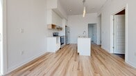 Located at 40 Kirkland Private in Ottawa, this well-appointed 2-bedroom, 1-bathroom unit offers a clean, modern aesthetic across a thoughtfully designed single floor. Light hardwood flooring runs consistently throughout the space, creating a warm and cohesive feel from room to room.

The kitchen is a standout feature, showcasing white cabinetry with open wood-accented shelving, a subway tile backsplash, stainless steel appliances including a full-size refrigerator and electric range, and a central island with a built-in sink and pendant lighting above — ideal for both meal preparation and casual dining.

The two bedrooms are bright and airy, benefiting from large windows that invite generous natural light and offer views of the surrounding neighbourhood and mature trees. The primary bedroom includes access to a dedicated closet, while the second bedroom features a double built-in closet, providing ample storage. Both rooms are finished with the same light hardwood floors and crisp white walls.

The bathroom is elegantly finished with large-format grey tile flooring, a full soaker tub with a glass-enclosed rainfall shower, a wall-mounted white vanity with a vessel sink and dark countertop, and a large mirror — creating a clean, spa-inspired atmosphere.

A hallway connects all rooms efficiently, and the unit also includes a dedicated closet for additional storage needs.