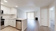 Located at 11615 Firestone Blvd in Norwalk, CA, this well-appointed one-bedroom, one-bathroom unit is thoughtfully designed to maximize its single-floor layout. Light-toned wood-style flooring flows throughout, creating a cohesive and airy feel across all rooms.

The open-concept living and dining area is bright and inviting, anchored by a classic fireplace and a full-width sliding glass door fitted with vertical blinds that fills the space with natural light and provides direct access to an outdoor patio. A built-in niche above the fireplace adds an architectural detail suited for display or media use.

The kitchen is efficiently designed with white shaker cabinetry, light quartz countertops, a peninsula with an integrated stainless steel dishwasher and sink, and a full suite of stainless steel appliances including a gas range, microwave, and refrigerator. Recessed lighting adds a clean, modern finish.

The bedroom is a comfortable and quiet retreat featuring a window with outdoor views, ample wall space, and access to a dedicated closet. The full bathroom offers white cabinetry, a single-sink vanity with a large mirror, and a combined tub and shower. The textured ceiling throughout adds subtle character to this clean, neutral interior.