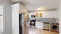 Located at 156 E Pulaski Rd in Huntington Station, NY, this single-floor residence at Eagle Rock Apartments offers a thoughtfully designed layout with a clean, modern aesthetic. Warm-toned hardwood floors flow throughout the living areas and bedrooms, complemented by soft, light-blue-grey walls and crisp white trim that create a calm and inviting ambiance.

The kitchen is a standout feature, equipped with a full suite of stainless steel appliances including a gas range, microwave, refrigerator, and dishwasher. White shaker-style cabinetry — some with frosted glass panels — lines the walls, paired with granite countertops and a classic subway tile backsplash, delivering both style and functionality.

The living area is open and well-lit, with natural light streaming in from multiple windows. Bedrooms continue the hardwood flooring theme and feature windows with outdoor views of the surrounding greenery. One bedroom includes a closet with built-in hanging storage, while radiator heating units provide efficient warmth throughout. The bathroom is finished with full white subway tile surround, a soaking tub, and a window for natural ventilation. The overall design balances classic residential character with updated, modern finishes.