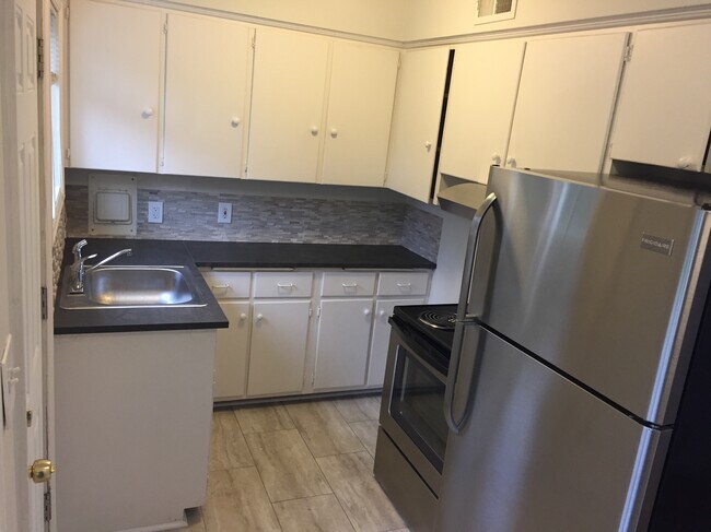 Cocina recién remodelada con encimeras nuevas, salpicadero, suelo de baldosas y electrodomésticos de acero inoxidable. - 7222 East Burnside