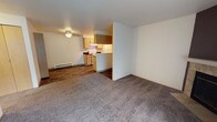 Located at 24028 SE 110th Pl, Unit N201 in Kent, Washington, this single-floor residence offers a practical and well-organized layout suited for comfortable everyday living. The open living and dining area features neutral carpet flooring and a baseboard heating system, creating a warm and functional common space. A half-wall partition separates the living area from the kitchen, maintaining an open connection between the two spaces while providing visual definition. The galley-style kitchen is efficiently designed with light wood cabinetry, dark countertops, tile flooring, and white appliances including a range, dishwasher, and refrigerator. Upper and lower cabinet storage provides ample space for kitchen essentials, and a ceiling-mounted light fixture keeps the area well-lit. The bedrooms are carpeted and generously sized, with neutral walls and flush-mount ceiling lighting. One bedroom features a walk-in closet with a built-in shelving rod, offering practical storage solutions. Another bedroom benefits from a window that brings in natural light and offers a view of surrounding greenery. Baseboard heaters are present throughout the unit for consistent climate control. Overall, the space presents a clean, straightforward design with functional finishes throughout.