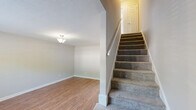 Located at 317 Atwood Dr in Burlington, NC, this two-story home offers a practical and comfortable layout spread across two floors. The main level features warm hardwood-style flooring throughout the living room and kitchen, creating a cohesive and inviting atmosphere. The living room is bright and open, with a staircase leading to the upper level and a closet for added storage. The kitchen is well-appointed with white cabinetry, dark countertops, stainless steel appliances including a refrigerator, dishwasher, range, and microwave, plus a window that brings in natural light. Both bathrooms are clean and functional, with one featuring a full tub-shower combination with a curved curtain rod. Upstairs, both bedrooms are carpeted and finished with neutral tones, each equipped with ceiling fans and windows that allow natural light to filter in. The primary bedroom offers a generous footprint, providing ample space for furnishings. Throughout the home, light gray walls, textured ceilings, and clean white trim create a neutral, move-in-ready aesthetic that is easy to personalize.