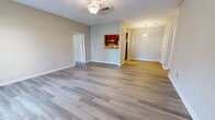 Located at 1290 W Government St in Brandon, Mississippi, this single-story residence offers a practical and comfortable layout across two bedrooms and two bathrooms. The open living area immediately impresses with its wide-plank wood-look flooring, neutral gray tones, and ceiling fan with decorative light fixture. Natural light filters in through a set of French doors, creating a bright and welcoming atmosphere throughout the main living space. The kitchen is accessible via a pass-through window from the living room and features rich, dark wood cabinetry, light granite-style countertops, and a full suite of stainless steel appliances including a refrigerator, range, microwave, and dishwasher. Light hardwood-style flooring carries through the kitchen as well. Both bedrooms are finished with plush carpeting and neutral wall tones, with the primary bedroom offering a generous footprint and natural light from a large window. The second bedroom, while more compact, maintains the same clean aesthetic. The bathrooms are functionally designed, with one featuring a shower/tub combination and wood-look flooring. Clean white trim and six-panel doors are consistent throughout, lending a cohesive and tidy finish to the entire home.