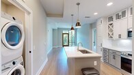 Located at 350 Caraway Crossing in Chapel Hill, NC, this well-appointed 2-bedroom, 3-bathroom residence offers a thoughtfully designed single-floor layout with modern finishes throughout. The open-concept kitchen serves as a central hub, featuring two-tone cabinetry with upper white shaker cabinets and lower gray cabinets, stainless steel appliances, a white quartz island with an undermount sink, stylish pendant lighting, and light hardwood flooring. The adjoining living room is bright and airy, with recessed lighting and a glass sliding door that opens to a balcony overlooking lush tree canopy views. Both bedrooms are carpeted and well-sized, each equipped with ceiling fans and floor-to-ceiling windows that frame serene outdoor greenery, filling the rooms with natural light. The primary bedroom benefits from generous proportions and direct access to a spa-inspired en-suite bathroom featuring a dual-sink vanity with taupe countertops, white cabinetry with matte black hardware, large-format tile flooring, and a tiled soaking tub surround. A walk-in closet with built-in shelving and hanging rods accompanies the primary suite. Additional bathrooms and two closets round out the functional layout, making this Chapel Hill residence a polished and practical home.