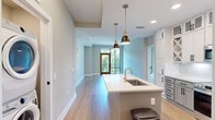Located at 350 Caraway Crossing in Chapel Hill, NC, this well-appointed 2-bedroom, 3-bathroom residence offers a thoughtfully designed single-floor layout with modern finishes throughout. The open-concept kitchen serves as a central hub, featuring two-tone cabinetry with upper white shaker cabinets and lower gray cabinets, stainless steel appliances, a white quartz island with an undermount sink, stylish pendant lighting, and light hardwood flooring. The adjoining living room is bright and airy, with recessed lighting and a glass sliding door that opens to a balcony overlooking lush tree canopy views. Both bedrooms are carpeted and well-sized, each equipped with ceiling fans and floor-to-ceiling windows that frame serene outdoor greenery, filling the rooms with natural light. The primary bedroom benefits from generous proportions and direct access to a spa-inspired en-suite bathroom featuring a dual-sink vanity with taupe countertops, white cabinetry with matte black hardware, large-format tile flooring, and a tiled soaking tub surround. A walk-in closet with built-in shelving and hanging rods accompanies the primary suite. Additional bathrooms and two closets round out the functional layout, making this Chapel Hill residence a polished and practical home.