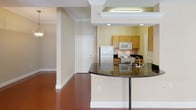 This single-floor residence is defined by its distinctive polished terra-cotta concrete floors, which flow continuously throughout the living spaces, bedrooms, and bathrooms, creating a cohesive and striking aesthetic. The open-concept living and dining area features a tray ceiling with crown molding and a ceiling fan, lending architectural depth to the space. French doors with large windows invite natural light and provide outdoor access, enhancing the airy feel of the main living area.

The kitchen is designed as a galley-style layout, equipped with light maple cabinetry, dark granite countertops, white appliances including a refrigerator, electric range, and dishwasher, and a double stainless steel sink. A curved granite-topped breakfast bar extends into the living area, offering a casual dining or entertaining option and creating a seamless visual connection between the kitchen and main living space.

The bedrooms are generously proportioned, each benefiting from natural light through blinded windows, and several feature ceiling fans. Additional rooms provide flexible use as bedrooms or office space. Both bathrooms echo the home's design language with light maple vanity cabinetry, dark granite countertops, large mirrors, and a combination tub-shower unit in the full bath. The overall ambiance is modern and clean with consistent, durable finishes throughout.