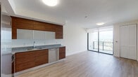 Located in the heart of Miami's Arts & Entertainment District, this modern unit at 46 NE Sixth St offers a thoughtfully designed open-concept layout with clean lines and contemporary finishes throughout. Light hardwood flooring flows seamlessly across the living and kitchen areas, creating a warm yet modern aesthetic.

The kitchen is a standout feature, outfitted with rich walnut-toned cabinetry, granite countertops, and a full suite of stainless steel appliances including a side-by-side refrigerator with ice maker, electric range, over-the-range microwave, and dishwasher. The L-shaped configuration maximizes workspace while keeping the kitchen open to the living area.

Floor-to-ceiling sliding glass doors lead to a private balcony, flooding the interior with natural light and offering expansive views of the Miami skyline. The bedroom benefits from the same floor-to-ceiling glazing, providing an airy, connected feel with striking cityscape views.

The bathroom is finished with white marble-style wall tile in the tub/shower surround, a granite-topped vanity with an undermount sink, and light tile flooring — delivering a clean, spa-like atmosphere. The unit's overall design reflects a refined urban lifestyle in one of Miami's most vibrant and centrally located neighborhoods.