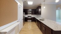 Located at 100 Holling FR in Frederick, MD, this single-floor residence offers a thoughtfully designed layout with a bright, open feel throughout. The spacious living area features warm hardwood-style flooring, crown molding, and neutral beige walls that create a clean, welcoming ambiance. Ample ceiling vents ensure consistent climate control, and the open flow into adjacent spaces makes the main living area feel generous and versatile. A built-in electrical panel is conveniently accessible from the living space.

The kitchen is well-equipped with rich dark cabinetry, granite countertops, a classic white subway tile backsplash, and stainless steel appliances including a refrigerator, range, and microwave. Pendant lighting and a skylight-style fixture brighten the workspace, while hardwood-style flooring continues the cohesive aesthetic.

The carpeted bedrooms offer a comfortable retreat, each featuring large windows with blinds that allow for abundant natural light and views of the surrounding area. The neutral tones and soft carpeting lend a calm, restful atmosphere.

The bathrooms are finished with dark espresso vanity cabinetry, white countertops, large mirrors, and elegant brushed nickel fixtures. One bathroom features a tiled walk-in shower with a glass enclosure and safety grab bars, reflecting a practical and accessible design. Tile flooring completes each bathroom's polished look.