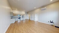 Located at 501 State St in Schenectady, NY, this thoughtfully designed 2-bedroom, 1-bathroom unit offers a clean, modern aesthetic throughout its single-floor layout. The open-concept living and kitchen area serves as the heart of the space, featuring light hardwood-style flooring, recessed lighting, and a wall-mounted mini-split HVAC unit. The kitchen is well-appointed with gray shaker-style cabinetry, granite countertops, and a full suite of stainless steel appliances including a range, over-the-range microwave, and refrigerator. The expansive living area provides generous room for flexible furniture arrangements. Both bedrooms are bright and airy, benefiting from natural light through multi-pane windows with views of the surrounding neighborhood. The primary bedroom offers a comfortable footprint, high ceilings, and its own mini-split unit for individualized climate control. The second bedroom mirrors the same clean finishes and light flooring. The bathroom features neutral large-format tile flooring and a tub-shower combination, maintaining a consistent, modern style. Throughout the unit, soft neutral wall tones, clean white trim, and consistent flooring create a cohesive and inviting atmosphere.