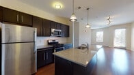 Located at 750 Summer St in Stamford, Connecticut, this modern single-floor residence offers a well-designed open-concept layout that seamlessly connects the kitchen and living areas. The kitchen is a standout feature, equipped with dark espresso cabinetry, granite countertops, stainless steel appliances including a gas range, microwave, refrigerator, and dishwasher, and a central island with a built-in sink and pendant lighting overhead. Rich hardwood flooring flows throughout the kitchen and living areas, adding warmth to the contemporary aesthetic. The spacious living room benefits from track lighting and large windows that invite natural light and offer views of the surrounding area, with access to an exterior door. An in-unit washer and dryer are conveniently tucked away near the kitchen. The bedrooms feature neutral-toned carpet flooring and well-sized windows that provide ample natural light and outdoor views. The bathrooms are finished in a clean, modern style with dark vanities featuring under-mount sinks, large mirrors, tile flooring, and tub-shower combinations with white subway tile surrounds. The overall design is cohesive and contemporary, offering a comfortable and functional living environment.