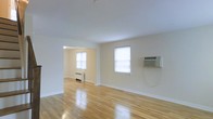 This two-floor space presents a straightforward, functional design with a warm and understated aesthetic. The main living area is characterized by gleaming hardwood floors that reflect natural light, contributing to a bright and open atmosphere. Neutral, off-white walls provide a clean backdrop throughout, lending the space a simple yet welcoming feel.

Two windows in the main living area allow natural light to filter in, keeping the space well-lit. A wall-mounted air conditioning unit provides climate control, while a baseboard radiator in the adjoining room offers supplemental heating. An arched passageway connects the main living area to an adjacent room, adding a subtle architectural detail that breaks up the open layout.

The overall design is minimal and practical, with clean lines and no ornate detailing. The polished hardwood flooring runs consistently through the visible areas, tying the rooms together visually. The space spans two floors, offering additional room and versatility beyond what is immediately visible. The combination of hardwood floors, neutral tones, and natural light creates a calm, livable environment suited to a variety of uses.