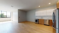 Located on Wilshire Boulevard in the heart of Los Angeles, this modern single-floor unit offers a clean, contemporary design throughout. Light hardwood flooring extends seamlessly across the open-concept living area, creating a bright and cohesive feel complemented by recessed lighting overhead.

The kitchen is a standout feature, equipped with stainless steel appliances including a refrigerator, range, microwave, and dishwasher. Crisp white upper cabinetry pairs with warm wood-toned lower cabinets, while a marble-style tile backsplash adds a refined touch. White quartz countertops provide ample prep space, and an in-unit front-loading washer is conveniently integrated into the kitchen layout. A wine or beverage cooler is also included.

The spacious living area offers an open, flexible floor plan bathed in natural light, with neutral grey walls that create a calm, modern ambiance. The bedroom is generously sized, featuring a built-in closet with shelving and a large window that invites natural light and garden views.

The bathroom is finished with vertical subway tile surrounding a full soaking tub and shower, complemented by a wood-vanity with a white countertop and geometric floor tile. The overall design is minimalist and move-in ready, reflecting the contemporary aesthetic of its Wilshire Corridor location.