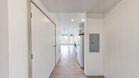 This efficiently designed studio unit at Koz 216 in Tacoma, WA offers a smart, modern layout across a single floor. A welcoming hallway entry leads into the heart of the unit, where the kitchen and living area flow together seamlessly. The kitchen is outfitted with sleek gray lower cabinetry and white upper cabinets, a stainless steel sink, flat-top cooktop, built-in microwave, and a full-size refrigerator — all set against clean white countertops and complemented by wood-look vinyl plank flooring that runs throughout the unit. The open living area benefits from large windows that frame street-level views of the surrounding Tacoma neighborhood, allowing natural light to fill the space. A ceiling fan adds functional comfort to the living area. The full bathroom features a tub/shower combo, a white vanity with modern hardware, and the same wood-look flooring, maintaining a consistent aesthetic throughout. Crisp white walls and recessed lighting contribute to a clean, contemporary feel. The unit's thoughtful design maximizes every square foot, making it a functional and modern living space in the heart of Tacoma.