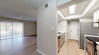 Located at 7315 W Hanna Avenue in Tampa, Florida, this single-floor residence offers a well-organized, open-concept layout designed for comfortable everyday living. The main living area is spacious and filled with natural light, featuring light wood-tone flooring, neutral-toned walls, and a textured ceiling. A large sliding glass door with vertical blinds opens to an outdoor area, allowing ample sunlight to flow through the room.

The kitchen is positioned adjacent to the living space and features a pass-through counter that connects both areas seamlessly. It is equipped with stainless steel appliances, including a refrigerator and range, complemented by gray cabinetry, white upper cabinets, and light countertops. A recessed tray ceiling with skylight-style lighting adds a distinctive architectural touch to the kitchen area.

The bedroom offers generous proportions with the same warm wood-tone flooring, a textured ceiling, and a sliding-door closet providing ample storage. The bathroom is finished with a marble-patterned countertop, an undermount sink with brushed nickel fixtures, a framed vanity mirror with overhead lighting, and clean white cabinetry. An adjacent entry hall with a louvered closet door adds practical utility to the layout. Overall, the space presents a clean, move-in-ready interior with consistent finishes throughout.
