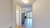 Located at 7711 MacLeod Trail SW in Calgary, this two-bedroom, one-bathroom unit offers a thoughtfully designed layout across a single floor. Light-toned vinyl plank flooring runs throughout the space, creating a clean, cohesive aesthetic complemented by neutral wall tones and white trim.

The kitchen is well-appointed with white cabinetry, a slate-tiled backsplash, white quartz-style countertops, and a full suite of stainless steel appliances including a refrigerator, electric range, over-the-range microwave, and dishwasher. A convenient in-suite stacked washer and dryer is tucked within the main living area, adding everyday practicality.

The two bedrooms are bright and functional, featuring light walls and ample room for furnishings. The primary bedroom includes a built-in sliding door closet, offering efficient storage. The full bathroom is finished with a white vanity, a large mirror with modern lighting, and a tiled tub-shower combination, all set on warm wood-toned flooring.

A private balcony with a glass railing extends the living space outdoors, offering open views of the surrounding greenery and cityscape — ideal for enjoying Calgary's sunny seasons. The unit's modern finishes and practical inclusions make it a well-rounded residential space.