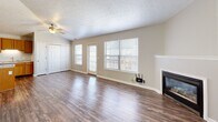 Located at Ravenwood Court in Lafayette, Indiana, this single-floor, three-bedroom, one-bathroom home offers a practical and comfortable layout. The combined kitchen and living room serves as the heart of the home, with the living area featuring rich hardwood-style flooring, a textured ceiling, large windows that bring in natural light, and a fireplace that serves as a welcoming focal point. The kitchen is well-equipped with warm oak cabinetry, granite-look countertops, a double-basin stainless steel sink, a dishwasher, electric range, and refrigerator, all complemented by track lighting overhead. The three bedrooms are carpeted and fitted with ceiling fans, each offering windows with exterior views and closet storage. The primary bedroom includes a spacious walk-in closet with wire shelving and hanging rods. The secondary bedrooms each feature their own standard closets with wire shelving. The full bathroom is finished with hardwood-style flooring, an oak vanity with a large mirror, and a full tub-shower combination. A hallway connects the private areas of the home, and the entry area provides two interior door access points. The neutral color palette throughout creates a clean, move-in-ready atmosphere.