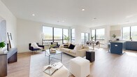 Unit 208 at 561 Northfield Ave in West Orange, NJ is a thoughtfully designed modern residence that combines contemporary aesthetics with functional living. The single-level unit is characterized by an open-concept layout that seamlessly connects the living, dining, and kitchen areas, creating a bright and airy atmosphere throughout.

The living area is anchored by expansive floor-to-ceiling windows framed in sleek black metal, inviting generous natural light and offering elevated views of the surrounding landscape. Light hardwood flooring runs throughout the space, complementing the clean white walls and recessed lighting overhead.

The kitchen features a striking two-tone design, pairing navy blue lower cabinetry with neutral upper cabinets and a crisp white countertop. A center island with bar seating, stainless steel appliances, and a gas range complete this well-appointed space.

The bedrooms are calm and understated, with continued hardwood flooring and ample natural light. The primary bathroom is finished with large-format marble-style tile flooring, a floating dark vanity with gold hardware, white quartz countertops, and a round gold-framed mirror. A secondary bathroom echoes the modern design with clean tile floors and minimalist fixtures, rounding out this polished West Orange residence.