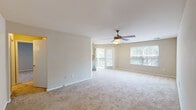 Located at 900 Golden Horseshoe Cir in Morrisville, NC, this single-floor residence offers a thoughtfully designed layout with a seamless flow between living spaces. The open living area is generously sized, featuring plush wall-to-wall carpeting, neutral-toned walls, and a ceiling fan with integrated lighting. Large windows fitted with blinds allow abundant natural light throughout, while sliding glass doors lead to a private balcony overlooking lush greenery outside.

The kitchen is efficiently designed with white shaker-style cabinetry, granite-style countertops, and wood-look flooring. Black appliances, including a refrigerator, range, built-in microwave, and dishwasher, complement the crisp cabinetry, and a window above the sink brings in additional daylight.

The bedrooms are carpeted and well-proportioned, each equipped with ceiling fans and windows that invite natural light. One bedroom features French doors opening to the outdoors, adding a distinctive touch. The bathrooms include a vanity with white cabinetry, a large mirror, contemporary lighting fixtures, wood-look flooring, and a tub-shower combination. Additional storage closets further enhance the functionality of this comfortable, move-in-ready home.