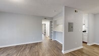This single-floor, three-bedroom, two-bathroom home in Clarkston, Georgia offers a practical and well-organized layout across a comfortable footprint. The living and dining areas are finished with durable wood-look flooring and soft gray walls, creating a clean, neutral aesthetic throughout. A standout feature of the living room is the set of French doors that flood the space with natural light and provide outdoor access, complemented by built-in shelving that adds both character and storage. The galley-style kitchen is efficiently designed with ample white cabinetry, light countertops, a double sink, and stainless steel appliances including a refrigerator, range, and dishwasher. The open pass-through connects the kitchen seamlessly to the main living area. The three bedrooms offer a quiet retreat, with the carpeted rooms providing a softer underfoot feel, while one bedroom features the same wood-look flooring as the main living spaces. Both bathrooms are finished in white with tub-shower combinations and wood-look flooring. A dedicated closet and hallways provide additional storage and connectivity throughout the home. Textured ceilings are consistent across the space, adding a classic touch to the overall interior design.