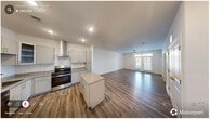Located in Durham, NC, this single-floor, 2-bedroom, 2-bathroom residence offers a thoughtfully designed open-concept layout that seamlessly connects the kitchen and living room. The kitchen is a standout feature, equipped with stainless steel appliances including a gas range, built-in microwave, dishwasher, and refrigerator. Gray shaker-style cabinetry, granite countertops, a wall-mounted range hood, and a central island provide ample prep and storage space. Wood-look laminate flooring runs throughout the main living areas and bathrooms, lending a warm, cohesive aesthetic. The living room is bright and inviting, highlighted by a ceiling fan, recessed lighting, and French doors with transom windows that fill the space with natural light and offer views of the outdoors. Both bedrooms feature plush carpeting, ceiling fans, and walk-in closets with wire shelving systems. The primary bedroom is generously sized, offering comfortable proportions. The two bathrooms are finished with granite-topped vanities, gray cabinetry, wood-look flooring, and tub-shower combinations. Clean white walls and neutral tones throughout create a fresh, modern atmosphere that is both functional and inviting.