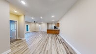 This single-floor unit offers a thoughtfully designed open-concept layout that seamlessly connects the kitchen and living areas. Light wood-look luxury vinyl plank flooring runs throughout the main living spaces, complemented by neutral beige walls and clean white trim that create a bright, cohesive aesthetic. Recessed lighting is installed throughout, and a ceiling fan anchors the spacious living area, which also features a glass-paned exterior door that brings in natural light.

The kitchen is a standout feature, equipped with warm honey-toned wood cabinetry, light granite countertops, and a full suite of stainless steel appliances including a refrigerator, range, microwave, and dishwasher. A peninsula with an integrated sink provides additional prep space and connects the kitchen to the open living area.

The bedrooms offer plush carpeting underfoot, recessed lighting, and generous proportions. The primary bedroom features a tray ceiling detail and a ceiling fan, adding architectural character to the space. Additional bedrooms are finished with the same luxury vinyl plank flooring as the main areas.

Both bathrooms mirror each other in design, each featuring a full tub-shower combination, a wood-cabinet vanity with granite countertops, and durable vinyl plank flooring. The overall design is clean, modern, and move-in ready.