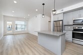 Located in Idaho Falls, ID, this thoughtfully designed single-story home offers four bedrooms, two bathrooms, and a well-appointed layout that maximizes every square foot. The open-concept kitchen and living area serves as the heart of the home, featuring light gray shaker-style cabinetry extending to the ceiling, granite-look countertops, a kitchen island with pendant lighting, and a full suite of stainless steel appliances including a refrigerator, range, microwave, and dishwasher. Light wood-look flooring flows throughout the main living areas, complementing the bright, neutral color palette. The living room is bathed in natural light through large windows with blinds and a full-light exterior door that opens to a private outdoor space. The four bedrooms are finished with plush carpet and recessed lighting, with some rooms featuring windows that invite additional natural light. The primary bedroom offers a comfortable footprint with a dedicated closet. Both bathrooms are finished with the same gray shaker cabinetry, granite-look countertops, and light wood flooring — one featuring a walk-in shower and the other a tub-shower combination with windows for ventilation. A dedicated laundry room houses a full-size top-load washer and dryer, adding everyday convenience to this clean, modern residence.