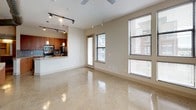 This thoughtfully designed 2-bedroom, 2-bathroom residence offers a seamless blend of modern finishes and functional living across a single floor. The open-concept living and dining area features gleaming polished tile flooring, a ceiling fan, and large windows that flood the space with natural light and outdoor views. An exposed duct detail adds an industrial accent to the otherwise clean, neutral aesthetic. The kitchen is outfitted with warm wood cabinetry, granite countertops, a glass tile backsplash, and a full suite of stainless steel appliances including a range, over-the-range microwave, and refrigerator. A pass-through counter connects the kitchen to the living area, enhancing the open flow. Track lighting provides ample illumination throughout. Both bedrooms are generously sized, featuring plush carpeting, ceiling fans, and large windows offering outdoor views. The primary bedroom includes a spacious walk-in closet with wire shelving. Each bathroom is finished with granite-topped vanities and rich wood cabinetry. The primary bath features a glass-enclosed walk-in shower with tile accents, while the second bath offers similar quality finishes. This residence delivers a polished, contemporary living experience.
