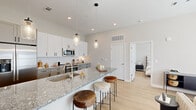 Located at 110 Addison Rd in Athens, Georgia, this well-appointed single-floor residence combines modern design with functional living. The heart of the home is a gourmet kitchen that immediately impresses with its expansive granite island, perfect for casual dining with seating for multiple guests. White upper cabinetry pairs elegantly with gray lower cabinets, all set against a classic subway tile backsplash. Stainless steel appliances, including a French door refrigerator, slide-in range, and built-in microwave, complete the chef-ready space. Pendant lighting overhead adds warmth and character. Light-toned luxury vinyl plank flooring runs throughout, lending the entire home a clean, cohesive aesthetic. The bedroom is a serene retreat, featuring large windows dressed with linen drapes and wood blinds that invite ample natural light while maintaining privacy. A second flexible room functions well as a home office or sitting area, also benefiting from generous window coverage and a bright, airy atmosphere. The bathroom is finished with large-format tile in the walk-in shower, a granite-topped vanity, and warm wood-tone flooring. A dedicated laundry room with stacked full-size washer and dryer and built-in shelving provides exceptional in-unit convenience. Throughout, the neutral color palette and thoughtful finishes create a modern yet inviting ambiance.