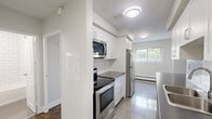 Located on Marland Avenue in Oshawa, Ontario, this well-appointed one-bedroom, one-bathroom unit offers a thoughtfully organized layout across a single floor. The living room is a highlight of the space, featuring rich parquet hardwood flooring, crisp white walls, and a sliding glass door that opens to a private balcony with pleasant outdoor views of surrounding greenery. Baseboard heating runs along the perimeter, ensuring year-round comfort.

The kitchen is modern and functional, outfitted with white cabinetry, subway tile backsplash, dark countertops, and a full suite of stainless steel appliances including a fridge, stove, and over-the-range microwave. Light tile flooring and a window allow natural light to brighten the space. A peninsula counter creates a practical divide between the kitchen and the adjacent living area.

The bedroom is a comfortable, well-sized room with the same classic parquet flooring, a window overlooking the outdoors, baseboard heating, and a mirrored sliding closet that adds depth and light to the room.

The bathroom is clean and bright, featuring white subway tile surrounding a full soaker tub and shower, a pedestal-style sink with a dark wood vanity, and tiled flooring, creating a fresh and timeless aesthetic throughout.