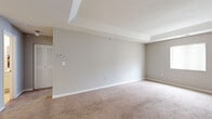 This single-floor residence offers a thoughtfully designed layout with a cohesive neutral color palette throughout. The living room serves as the heart of the home, featuring wood-look flooring, natural light from multiple windows, and direct access to an exterior door — creating an open, airy atmosphere. A dedicated dining area sits adjacent to the living space, highlighted by a pendant light fixture and wood-look flooring that ties seamlessly into the rest of the common areas. The kitchen is equipped with white cabinetry, light stone-look countertops, black appliances including a refrigerator, electric range, and dishwasher, as well as a peninsula that provides additional prep space and visual separation from the entry. The home includes two well-proportioned bedrooms, each finished with plush carpeting, neutral walls, and windows that allow natural light to filter in. A secondary room off the main living area offers versatility with wood-look flooring and an exterior door. The full bathroom features a shower-tub combination, a vanity with mirror, and wood-look flooring. Throughout the residence, clean lines, consistent finishes, and a muted tonal palette contribute to a calm, modern ambiance well-suited for comfortable everyday living.