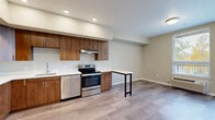 Located at 375 Osprey Ln in Independence, Oregon, this thoughtfully designed one-bedroom, one-bathroom unit offers an efficient and modern living experience across a single floor. The open-concept layout seamlessly combines the living room, dining area, and kitchen into one cohesive space, making excellent use of every square foot. Light wood-look flooring runs throughout, complementing the neutral warm-beige walls and recessed lighting overhead.

The kitchen is a standout feature, outfitted with rich warm-toned wood cabinetry, white quartz countertops, and a full suite of stainless steel appliances — including a side-by-side refrigerator with ice maker, electric range with range hood, and dishwasher. A built-in bar-height counter extends from the kitchen, providing a practical dining or workspace area.

The bedroom is a comfortable, well-proportioned retreat featuring light-filled windows with exterior views and a sliding closet for storage. An additional closet provides extra organizational space. The full bathroom features tile flooring, a soaking tub with shower combination, a wood-trimmed vanity with white countertop, and recessed lighting.

A dedicated laundry room with a full-size washer and dryer adds everyday convenience. Clean lines, contemporary finishes, and a functional floor plan define this well-appointed Independence residence.