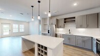 Located at 2400 Buckner Ln in Spring Hill, TN, this well-appointed single-story home offers 3 bedrooms, 2 bathrooms, and a thoughtfully designed open floor plan. The combined kitchen and living area serves as the heart of the home, showcasing gray shaker-style cabinetry, white quartz countertops, a classic subway tile backsplash, and stainless steel appliances. A central island with built-in wine storage and stylish pendant lighting adds both function and character to the space. Light hardwood flooring flows throughout the main living areas, complementing the bright, neutral palette. The primary bedroom features direct access to a private balcony through a glass door, allowing abundant natural light and outdoor views. Additional bedrooms are carpeted, include natural light from windows, and offer walk-in closets with built-in shelving. One bedroom also features built-in shelving and a desk nook. The bathrooms are finished with gray vanities, white quartz countertops, matte black hardware, and large-format tile flooring. The home also includes a dedicated laundry room and utility room. With four closets throughout, storage is plentiful. The clean, modern aesthetic and functional layout make this Spring Hill home a standout.