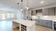 Located at 2400 Buckner Ln in Spring Hill, TN, this well-appointed single-story home offers 3 bedrooms, 2 bathrooms, and a thoughtfully designed open floor plan. The combined kitchen and living area serves as the heart of the home, showcasing gray shaker-style cabinetry, white quartz countertops, a classic subway tile backsplash, and stainless steel appliances. A central island with built-in wine storage and stylish pendant lighting adds both function and character to the space. Light hardwood flooring flows throughout the main living areas, complementing the bright, neutral palette. The primary bedroom features direct access to a private balcony through a glass door, allowing abundant natural light and outdoor views. Additional bedrooms are carpeted, include natural light from windows, and offer walk-in closets with built-in shelving. One bedroom also features built-in shelving and a desk nook. The bathrooms are finished with gray vanities, white quartz countertops, matte black hardware, and large-format tile flooring. The home also includes a dedicated laundry room and utility room. With four closets throughout, storage is plentiful. The clean, modern aesthetic and functional layout make this Spring Hill home a standout.