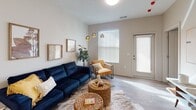 This single-floor residence is thoughtfully designed with a modern, open-concept layout that seamlessly connects the main living areas. The kitchen serves as a central hub, outfitted with crisp white shaker cabinetry, stainless steel appliances including a range, microwave, and refrigerator, and a generous granite-topped island with an undermount sink and bar seating. A subway tile backsplash and pendant lighting add refined detail, while light wood-style flooring extends throughout.

The living area flows naturally from the kitchen, providing ample space for entertaining. Large windows invite natural light, complemented by a private entry door. The bedroom is carpeted and benefits from natural sunlight streaming through its window, creating a warm, restful atmosphere.

A dedicated office or flex room features carpet flooring, a ceiling fan, and broad windows that allow abundant daylight, making it well-suited for remote work or study. The bathroom is finished with wood-style flooring, a single vanity with granite countertop, a large mirror, and matte black fixtures. A utility closet with hookups rounds out the functional layout, contributing to the unit's practical and well-organized design.