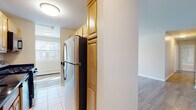 Located at 195 Admiral Kalbfus Rd in Newport, Rhode Island, this single-floor unit offers a clean, functional layout designed for comfortable everyday living. The galley-style kitchen is well-equipped, featuring warm honey-toned wood cabinetry with ample storage, dark granite countertops, tile flooring, stainless steel appliances including a full-size refrigerator and gas range, and a built-in dishwasher. The kitchen opens toward the living areas, creating a connected flow throughout the unit. The living and bedroom spaces are finished with light wood-tone laminate flooring and neutral-toned walls, lending a bright, airy feel. Multiple windows allow generous natural light to fill the rooms, with views of the surrounding neighborhood. Each room is equipped with baseboard heating, and wall-mounted air conditioning units provide climate control year-round. The bathroom features a full tub and shower combination with a clean white surround, tile flooring, and a vanity with storage. The overall layout is practical and well-organized, offering clearly defined living, sleeping, and kitchen zones. With its updated finishes and convenient Newport location near local amenities, this space provides a comfortable and functional living environment.