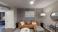 This single-floor residence showcases a thoughtfully designed layout that blends industrial and contemporary aesthetics. The living area serves as a central focal point, anchored by a striking concrete-panel feature wall with structural detailing that adds texture and visual depth. The space accommodates a sectional seating arrangement alongside a geometric coffee table, creating a cohesive and comfortable gathering area.

The kitchen is efficiently designed with dark lower cabinetry contrasted by white upper shaker-style cabinets and a white subway tile backsplash. Dark granite countertops and a full suite of stainless steel appliances, including a French door refrigerator, electric range, and built-in microwave, complete the space. Large windows in the kitchen provide city views and natural light.

The bedroom features soft carpeting, neutral gray walls, and direct access to both the bathroom and an additional room, likely a walk-in closet or secondary space. Wall-mounted sconces flank the bed, complemented by a circular mirror above. The bathroom includes large-format tile flooring, a dark vanity with an oval mirror, pendant lighting, and direct bedroom access, offering a functional and polished finish.