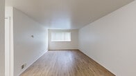This single-floor residence offers a functional and efficient layout with two bedrooms, one bathroom, and a combined kitchen and living area. Throughout the main living spaces, light wood-tone laminate flooring adds warmth and continuity, while crisp white walls create a clean, bright atmosphere.

The open kitchen and living room area is a central feature of the home. The kitchen is equipped with white appliances, including a coil-top electric range and refrigerator, complemented by rich wood-toned cabinetry and light marble-patterned countertops. White subway tile backsplash lines the cooking area, adding a classic touch. A window fitted with vertical blinds allows natural light to fill the living space.

The primary bedroom is generously proportioned, featuring hardwood-style flooring and a large window dressed with vertical blinds, allowing natural light and outdoor views. The second bedroom is finished with plush carpeting and its own window overlooking greenery outside, creating a comfortable and serene retreat. A built-in closet with bi-fold doors provides convenient storage in this room.

The bathroom is well-appointed with wood-toned cabinetry, a white countertop vanity, hardwood-style flooring, and a tiled bathtub and shower surround. A dedicated closet rounds out the layout, providing additional storage for the home.