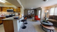 Located at 6475 36th Ave NW in Norman, Oklahoma, this single-floor residence offers a thoughtfully designed open-concept layout that seamlessly connects the kitchen, dining, and living areas. The kitchen is well-equipped with warm honey-toned cabinetry, granite-style countertops, stainless steel appliances including a microwave and electric range, a full-size refrigerator with ice maker, and tile flooring. A breakfast bar with bar seating provides a casual dining option and serves as a natural divider between the kitchen and the main living space. The open living and dining area features plush carpeting, neutral-toned walls, and a glass door that invites natural light while providing outdoor access. The living room offers a comfortable, welcoming atmosphere highlighted by large windows. The bedroom is a restful retreat complete with carpeted floors, a ceiling fan, a window with outdoor views, and ample closet space. The bathroom is finished with large-format tile flooring, a wood-vanity with a marble-style countertop, a well-lit mirror, and convenient access to a walk-in closet. Throughout the space, five-panel interior doors and consistent neutral finishes contribute to a cohesive and functional living environment.
