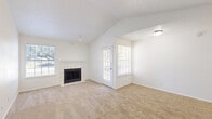 This single-floor, 2-bedroom, 2-bathroom residence offers a thoughtfully designed layout that maximizes both comfort and functionality. The living room serves as the centerpiece of the home, featuring dramatic vaulted ceilings, a tiled wood-burning fireplace, and multiple windows that flood the space with natural light and offer views of surrounding greenery. Soft wall-to-wall carpeting runs throughout the living and bedroom areas, adding warmth underfoot.

The kitchen is efficiently laid out in a galley-style configuration, equipped with white cabinetry, ample counter space, a stainless steel sink, an electric range, and a dishwasher. Dark hardwood-style flooring grounds the kitchen and flows into the bathrooms, providing a clean contrast to the bright white cabinetry and fixtures. Each bathroom includes a single vanity with a large mirror and a shower-tub combination.

Both bedrooms are well-proportioned, carpeted spaces with large windows that invite natural light and outdoor views. The primary bedroom offers generous square footage with room for a full furniture arrangement. Three closets distributed throughout the unit provide ample storage. An entrance and dedicated hallway complete the layout, creating a practical flow between all areas of the home.