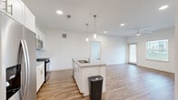 This well-appointed 2-bedroom, 2-bathroom residence is designed with a clean, modern aesthetic and thoughtful layout across a single floor. The open-concept kitchen and living area forms the heart of the home, centered around a kitchen island with a granite countertop, undermount sink, and stylish pendant lighting. The kitchen is fully equipped with stainless steel appliances—including a gas range, microwave, and refrigerator—complemented by white shaker cabinetry with brushed nickel hardware and a classic tile backsplash. Warm hardwood-style flooring flows seamlessly throughout the main living areas and bedrooms, enhancing the bright, airy atmosphere created by white walls and recessed lighting. The spacious primary bedroom features a ceiling fan, access to a dedicated bathroom with a granite vanity, glass-enclosed walk-in shower, and tile flooring. The second bedroom is generously sized with natural light from a large window and its own ceiling fan. The second bathroom offers a full soaking tub with tiled surround and a granite vanity. Additional features include a dedicated entrance, an in-unit closet, and a ceiling fan in the living area. The overall ambiance is clean, contemporary, and move-in ready.