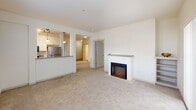 Located at 436 Broadway in downtown Tacoma, WA, this 3-bedroom, 2-bathroom apartment offers a well-designed single-level layout. The open-concept living and kitchen area forms the heart of the home, where a peninsula with a built-in sink and dark countertops separates the two spaces. The kitchen is equipped with stainless steel appliances, white cabinetry extending to the ceiling, hardwood-style flooring, and pendant lighting that adds a modern touch. The living room features plush carpeting, a built-in fireplace with a clean white surround, and large sliding glass doors with vertical blinds that invite natural light and outdoor views. Each of the three bedrooms is carpeted and includes a sliding-door closet with built-in shelving for organized storage. The primary bedroom benefits from its own en-suite bathroom and a generously sized closet. Both bathrooms are well-appointed with tub/shower combinations, clean white tile surrounds, and vanities with undermount sinks. One bathroom features warm wood-tone flooring and classic fixtures, while the other showcases a light stone-finish countertop and a large mirror. The overall aesthetic is clean, neutral, and functional throughout.