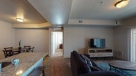 Located at 311 NW 96th St in Kansas City, Missouri, this single-floor residence offers a functional and comfortable layout with thoughtfully designed living spaces throughout. The open living area features plush carpeting, a vaulted ceiling with textured finish, and a sliding glass door that opens to a private balcony, allowing natural light to fill the room. A rustic wood media console serves as a focal point for the entertainment area, complemented by coordinating area rugs that add warmth and character. Adjacent to the living space is a cozy dining nook with hardwood-style flooring and a round wooden table, ideal for intimate meals. The kitchen is well-equipped with rich dark cabinetry, granite countertops, black appliances including a refrigerator, electric range, and built-in microwave, all set atop durable wood-style flooring. The bedroom is bright and welcoming, with multiple windows that invite natural light, soft carpeting, and ample space for furnishings. A wooden dresser with a large mirror adds both function and style. The two bathrooms each feature wood-style flooring, dark vanity cabinetry with granite countertops, and shower/tub combinations, offering a clean and cohesive aesthetic throughout this well-maintained residence.