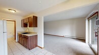 This single-floor, 3-bedroom, 1-bathroom unit offers a practical and well-organized layout designed to maximize functionality. The kitchen is equipped with rich dark wood cabinetry, light countertops, a built-in sink, and a white electric range with an overhead exhaust hood. Tile flooring anchors the kitchen area, which opens seamlessly into a generously sized carpeted living space. The living area is bright and open, featuring a sliding glass door that leads to a private balcony with outdoor views, complemented by a window-mounted air conditioning unit and baseboard heating.

Each of the three bedrooms is carpeted and features neutral walls, warm wood-toned trim and doors, and built-in louvered bi-fold closets offering ample storage. The spacious primary bedroom includes a ceiling fan for added comfort. Additional bedrooms also feature ceiling fans and windows that bring in natural light.

The bathroom is clean and straightforward, featuring a full tub-shower combination with white square tile surround and a curtain rod. Baseboard heating is present throughout the unit, ensuring consistent warmth. A connecting hallway ties the rooms together, creating a cohesive and easy-to-navigate floor plan throughout this functional, move-in ready space.