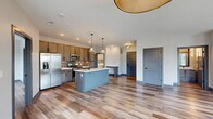 Located at 1155 S Rangeline Rd in Carmel, Indiana, this well-appointed 2-bedroom, 2-bathroom residence offers a thoughtfully designed single-floor layout. The open-concept kitchen and living area serves as the heart of the home, showcasing rich hardwood-style flooring that extends throughout. The kitchen is equipped with stainless steel appliances, including a gas range, microwave, and French door refrigerator, complemented by warm taupe cabinetry, a decorative tile backsplash, and a central island featuring a built-in wine rack and pendant lighting overhead. A private balcony door brings in natural light and outdoor views, enhancing the airy feel of the living space. Both bedrooms are generously sized, with large windows that frame views of the surrounding Carmel streetscape and flood the rooms with natural light. Ceiling fans add comfort, and each bedroom is paired with a dedicated closet—one being a spacious walk-in with built-in shelving and hanging rods. The bathrooms feature modern finishes with clean tile work. A dedicated in-unit laundry room with a full-size washer and dryer adds everyday convenience. Gray-toned door frames and trim provide a contemporary contrast throughout, tying the modern aesthetic together cohesively.
