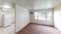 This single-floor unit offers a straightforward and functional layout designed for comfortable everyday living. The floor plan includes a spacious living area finished with wall-to-wall carpeting, neutral-toned walls, and a large window that overlooks a green outdoor courtyard area, filling the room with natural light. A wall-mounted air conditioning unit and baseboard heating provide year-round climate control.

The kitchen is efficiently designed with warm oak cabinetry, dark laminate countertops, and a double-basin sink positioned beneath a window. White appliances, including a full-size refrigerator and a gas range, are included. The resilient flooring in the kitchen provides easy maintenance and durability.

The bedroom is a well-proportioned, carpeted room featuring a window with views of the surrounding neighborhood and a textured ceiling with a central light fixture. Baseboard heating keeps the room comfortable through colder months.

The bathroom is outfitted with a full tub-and-shower combination, featuring large-format tile surround in a neutral tone. Oak cabinetry beneath the vanity provides storage, and a drop-panel ceiling completes the space.

Throughout the unit, warm wood-trimmed interior doors and light-toned baseboards contribute to a cohesive, understated aesthetic. The unit is clean, move-in ready, and well-suited for those seeking a practical and comfortable living space.
