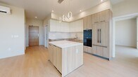 This modern residence in Roseville, CA offers a thoughtfully designed single-floor layout with 2 bedrooms, 2.5 bathrooms, and a seamless open-concept flow. Light wood flooring runs throughout the home, complementing the clean, neutral palette and contemporary finishes.

The designer kitchen is a standout feature, showcasing a center island with a crisp white quartz countertop, two-tone cabinetry in white and warm wood-grain, stainless steel fixtures, built-in double ovens, and a statement ring pendant chandelier. The kitchen opens directly to the living area, which is bathed in natural light from expansive floor-to-ceiling windows framing outdoor views of the surrounding Roseville streetscape and tree canopy.

The spacious primary bedroom features its own ensuite bathroom with an illuminated vanity mirror and wood-toned cabinetry, as well as a dedicated walk-in closet with built-in shelving and drawer units. The second bedroom is equally bright, with large windows inviting generous natural light. A half bathroom serves guests with a modern vessel sink, wood vanity, and backlit mirror.

Each room reflects a cohesive modern aesthetic — clean lines, recessed lighting, and a warm, minimalist sensibility that creates a bright and welcoming living environment.