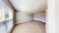 This single-floor space offers a well-designed layout that balances character with modern updates throughout. The living area serves as a standout feature, showcasing a full whitewashed brick accent wall that adds texture and visual interest against neutral-toned walls and light wood-look flooring that flows seamlessly throughout the unit. Ceiling fans are present in multiple rooms, providing both function and comfort.

The kitchen is thoughtfully appointed with crisp white cabinetry, granite-look countertops, a tile backsplash, and a full suite of stainless steel appliances including a range, microwave, and dishwasher. The layout provides ample workspace and storage for everyday use.

The bedrooms continue the cohesive aesthetic, each featuring the same light wood-look flooring, neutral wall tones, ceiling fans, and windows that allow natural light to filter in. One bedroom also features the signature whitewashed brick accent wall, creating a striking and consistent design thread.

The bathroom is clean and contemporary, featuring a wood-tone vanity with a white basin sink, matte black fixtures, a framed mirror with medicine cabinet, and a full soaking tub with shower. The whitewashed brick detail carries into the bathroom as well, tying the overall design together with a cohesive, modern-rustic aesthetic.